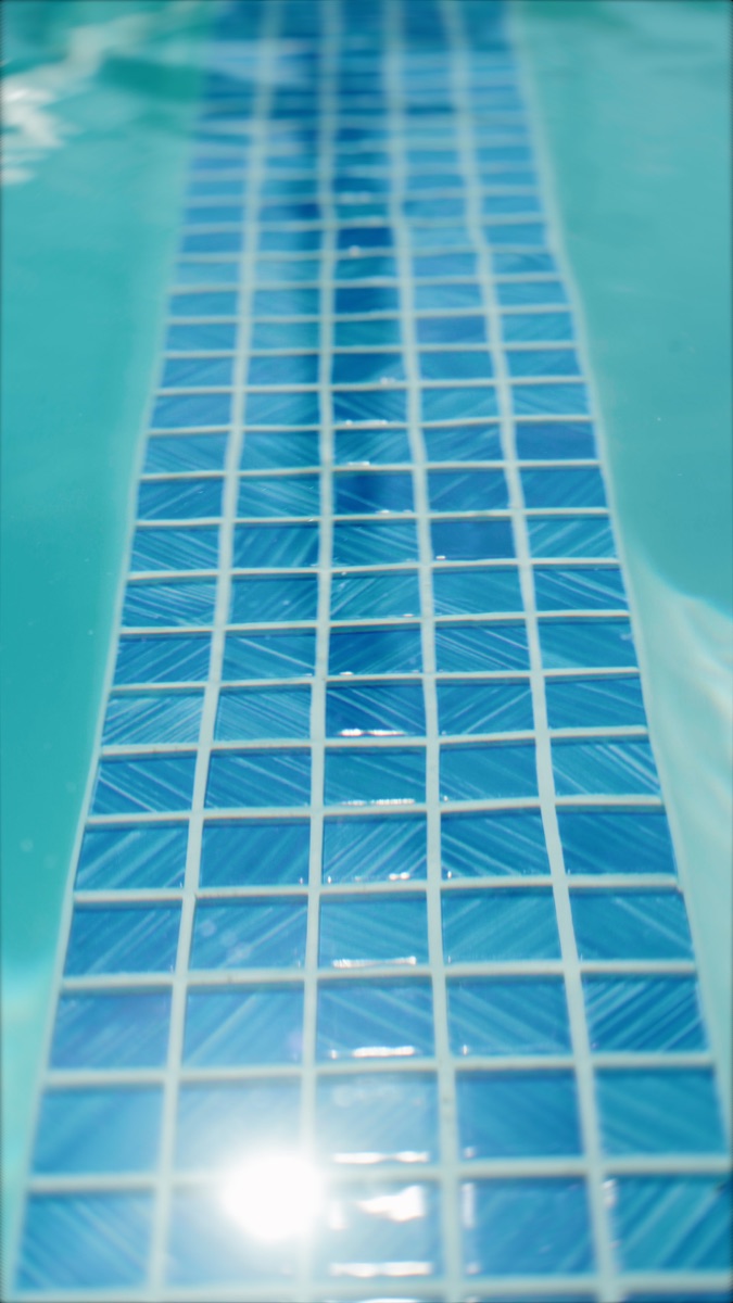 Detalhe das pastilhas azuis da piscina sob a água em movimento
